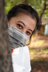 Close-up portrait of young woman standing outdoors wearing mask