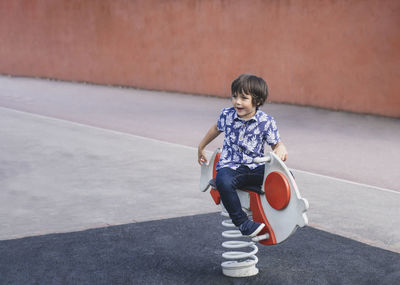 Boy looking away while sitting on play equipment
