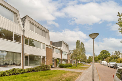 Empty road by building against sky