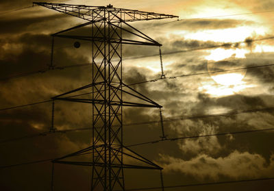 Low angle view of silhouette electricity pylon against sky