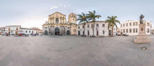 Panoramic view of buildings by road against sky