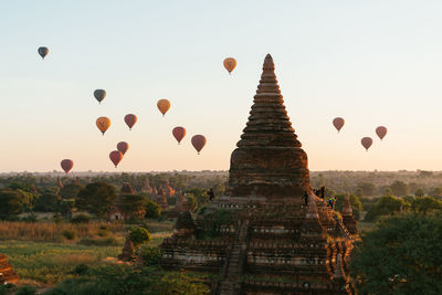 View of hot air balloons over temple against sky