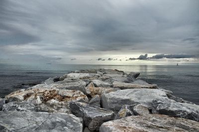 View of rocky beach against cloudy sky