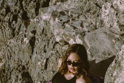 High angle view of woman wearing sunglasses sitting on rock formation