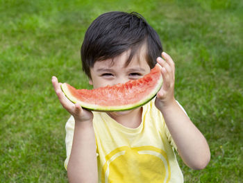 Portrait of boy holding watermelon while standing outdoors