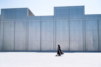 Side view of woman standing on building in city