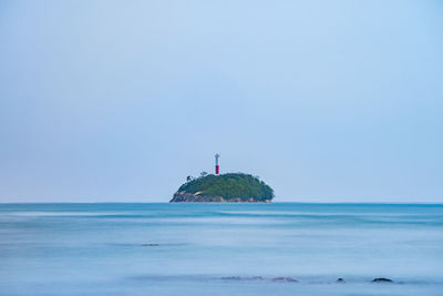 Lighthouse on sea against clear sky