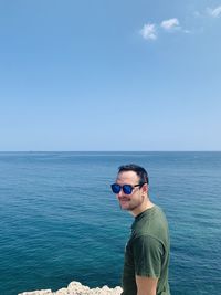 Portrait of young man standing in sea against sky