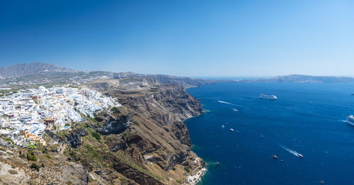 High angle view of townscape by sea against clear blue sky