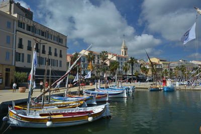 Boats moored in canal amidst buildings against sky