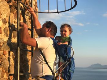 Father and son standing against sky