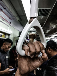 Cropped hand of man holding handle in train