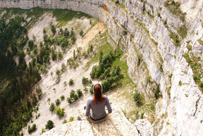 Rear view of woman sitting on rock