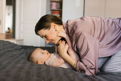 Loving mother looks at her baby lying on the bed