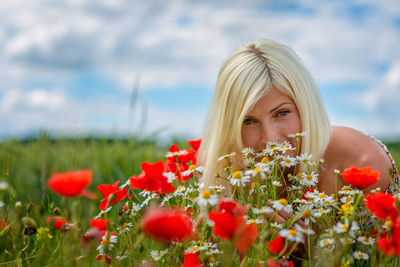 Portrait of woman by flowers blooming in field