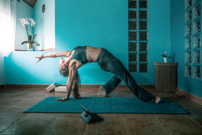 Full length of woman with arms raised on floor