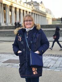 Portrait of smiling mature woman standing on footpath