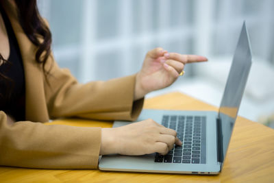 Midsection of woman using mobile phone while sitting on table