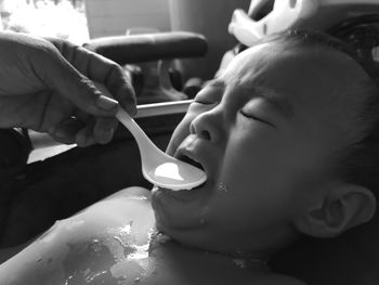 Close-up of hand feeding crying baby boy water