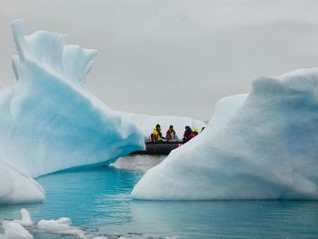 People in sea against sky during winter