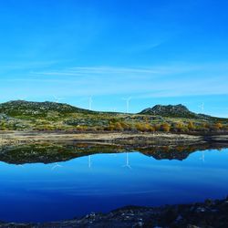 Scenic view of lake by mountain against blue sky