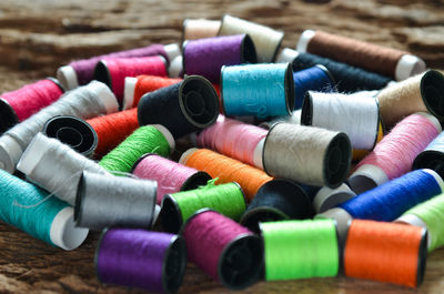 Close-up of multi colored spools on wood