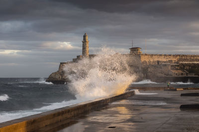 Sea waves splashing on shore against sky