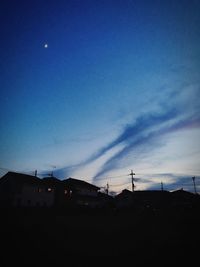 Low angle view of silhouette houses against blue sky