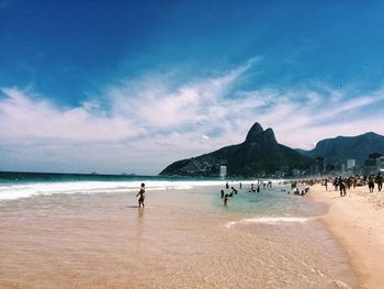 People at beach against blue sky