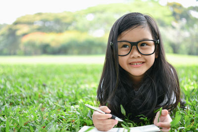 Close-up cute girl with book and pen on field