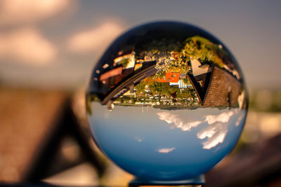 Close-up of crystal ball on glass against sky