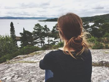 Rear view of woman standing by river against sky