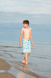 Full length of shirtless boy standing on beach