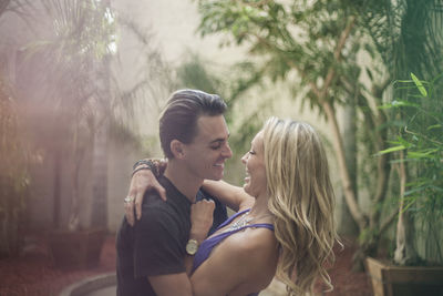 Young couple kissing against trees