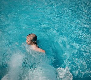 High angle view of shirtless boy swimming in pool