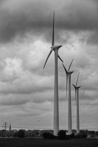 Windmills on field against sky