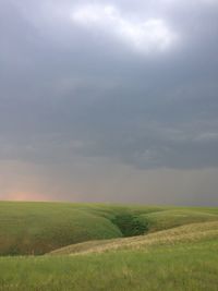 Scenic view of grassy field against cloudy sky