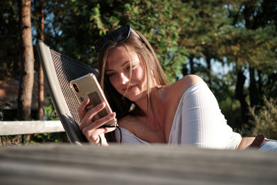 Beautiful smiling woman using smart phone sitting outdoors