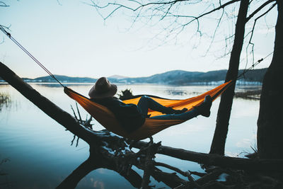 Rear view of man sitting on boat in lake against sky