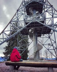 Rear view of man sitting on bridge against sky