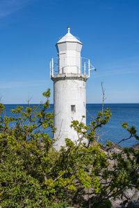 Lighthouse by sea against sky