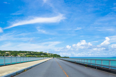 Road leading towards bridge against sky