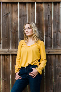 Portrait of beautiful woman standing against fence