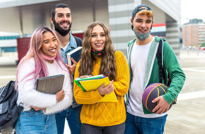 Cheerful friends carrying book outdoors