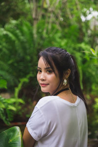 Portrait young asian woman in white t-shirt looking at a camera with nature background.