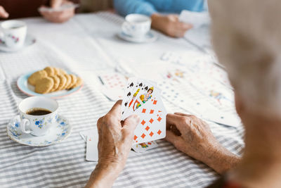 Cropped image of senior woman playing cards with family at table