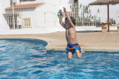 Full length of woman with arms raised in swimming pool