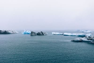 Scenic view of icebergs in sea against sky during foggy weather