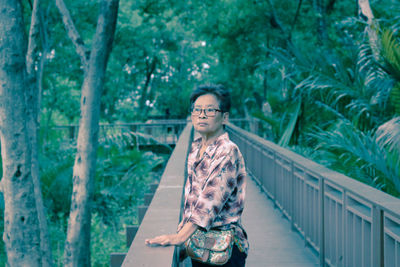 Mature woman standing on footbridge in forest