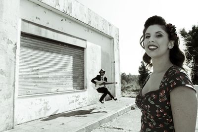 Young woman smiling while standing against sky